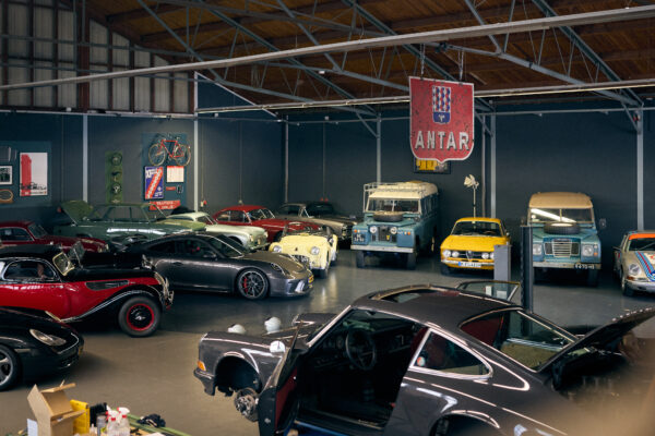 showroom full of classic cars like porsche 911 bmw landrover 110 alfa rome 1750 triumph tr3